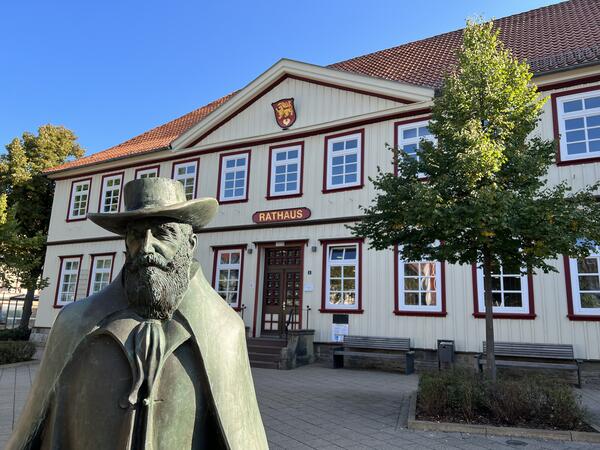 Bild vergr&ouml;&szlig;ern: Abgebildet ist die Bronzefigur von Wilhelm Busch vor dem Seesener Rathaus bei Sonnenschein. 