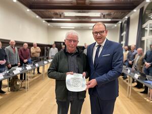 Bild vergr&ouml;&szlig;ern: Horst Adam h&auml;lt gemeinsam mit B&uuml;rgermeister Erik Homann den Wappenteller w&auml;hrend der Ratsitzung. 
