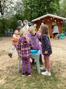 Bild vergr&ouml;&szlig;ern: Abgebildet ist eine kleine Gruppe Kinder beim Riesen-Seifenblasen-Pusten.