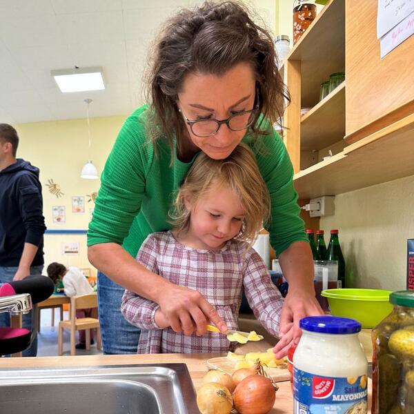 Bild vergr&ouml;&szlig;ern: Kita Spottberg_Erzieherin Inna Jurk assistiert beim Schneiden der Kartoffeln